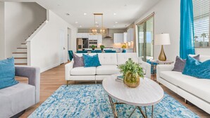 Ein modernes Wohnzimmer mit einem weißen Sofa, einem runden Couchtisch und einem blau gemusterten Teppich.