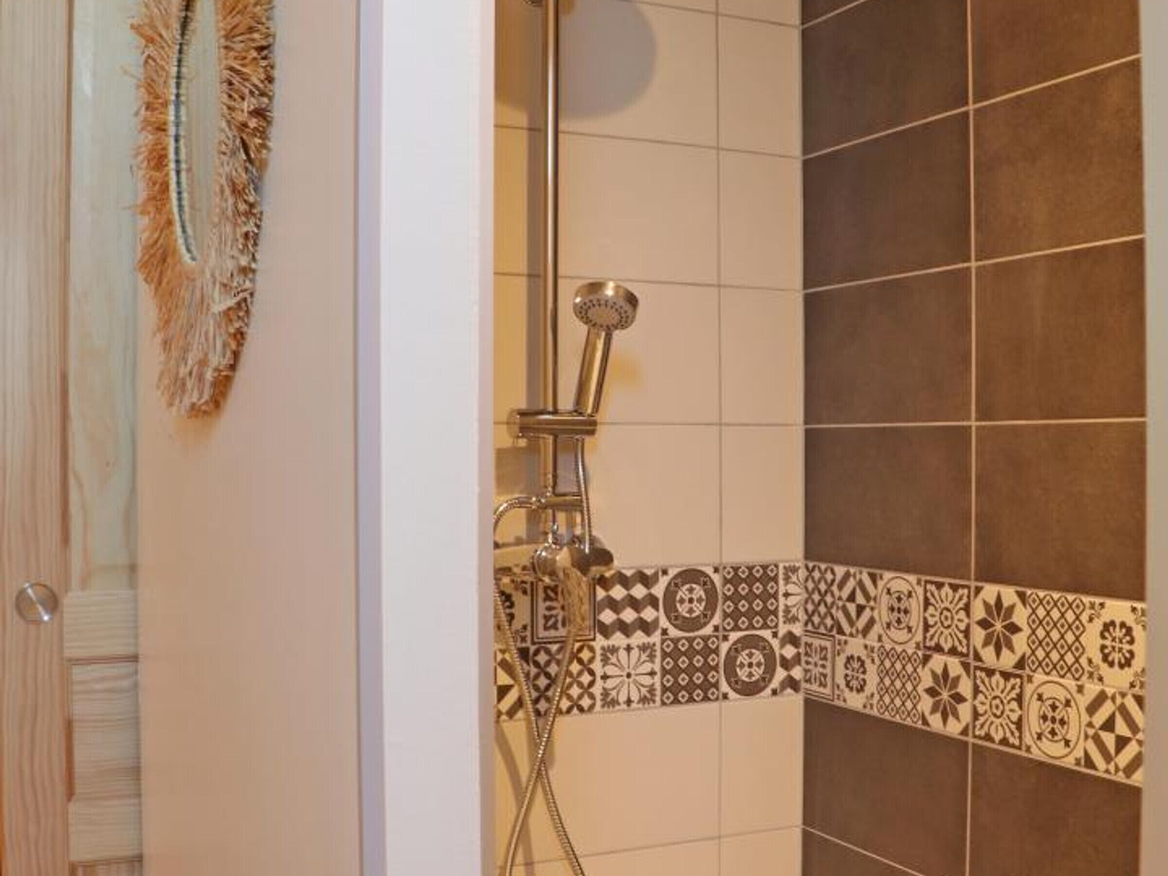 A shower area with a patterned tile border and a hanging towel.