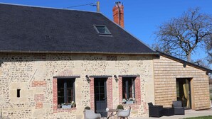 Une maison en pierre à deux étages, avec un toit en pente, une cheminée et une petite fenêtre.