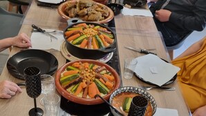 A long dining table with various dishes, including roasted meats and vegetables, set for a meal.