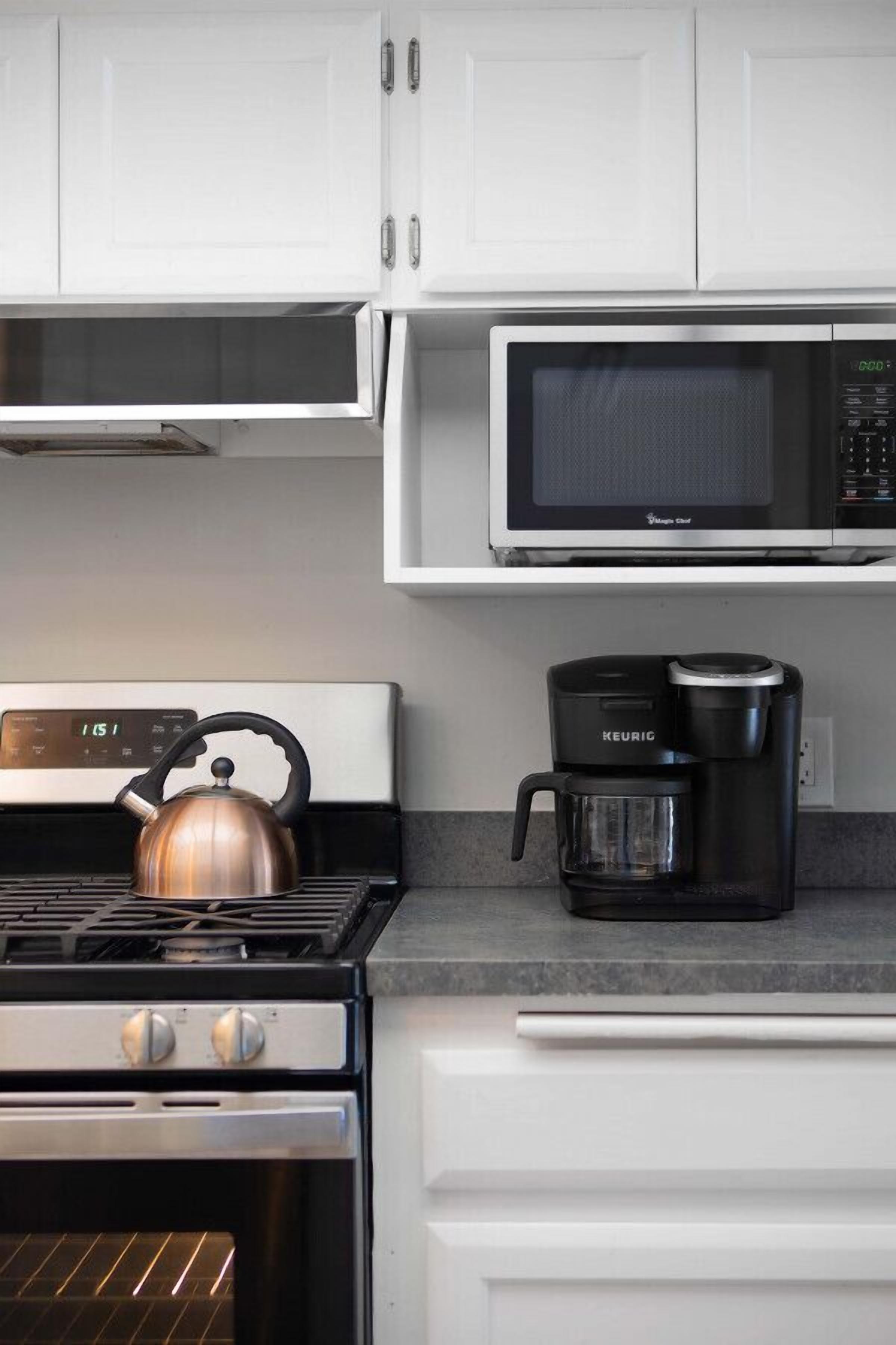 Une cuisine équipée d’une cuisinière, d’une bouilloire, d’un four à micro-ondes et d’une machine à café.