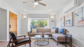 Ein modernes Wohnzimmer mit Sofa, Sessel, Couchtisch und Deckenventilator.