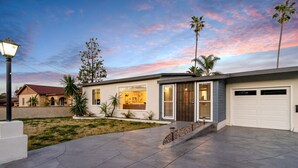 Ein modernes Haus mit Garage, gepflegtem Rasen und Palmen.