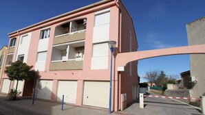 A multi-story residential building with balconies, a gated entrance, and a clear sky. - Charming T2 Apartment with Private Garage and Balcony in Central Village (Balaruc-les-Bains)