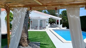 A pool area with a pergola, a covered seating area, and a white building in the background. - Beautiful Villa with Pool, Near Beach and Marina, Sleeps 7 (L'Ametlla de Mar)