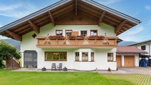 A two-story chalet with a wooden balcony, large windows, and a covered patio area. - Holiday Home in a Beautiful Location (Radstadt)