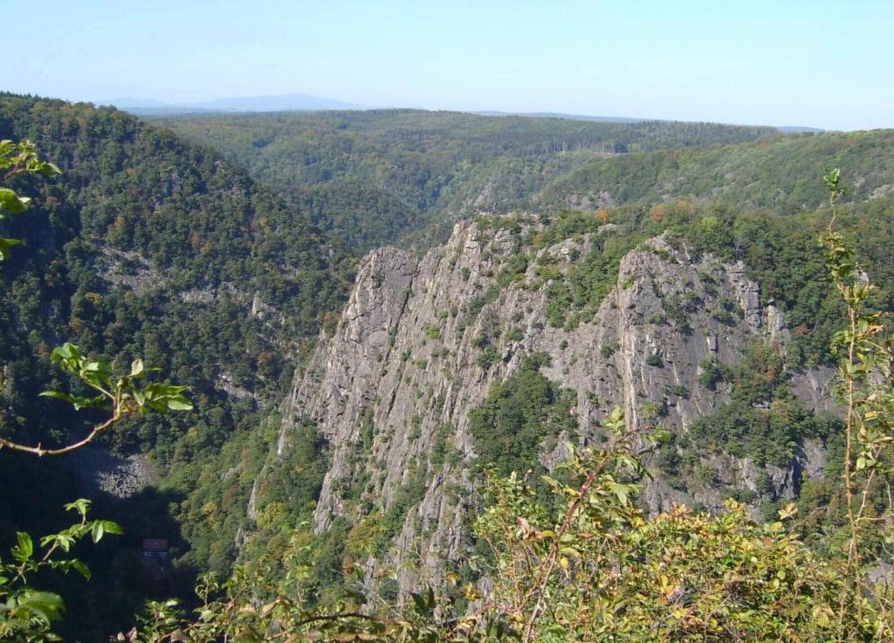 Un paysage montagneux caractérisé par une forêt dense et de hautes falaises rocheuses.