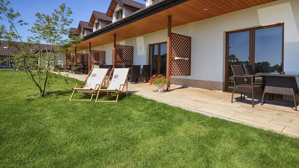 A modern residential building with a covered patio area, outdoor seating, and a well-maintained lawn. - Duplex Apartments 300 m From the Sea. Living Room, 2 Bedrooms, own Terrace (Darlowo)