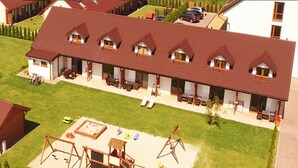 A model of a building with a sloped roof, multiple windows, and a patio area with outdoor furniture. - Duplex Apartments 300 m From the Sea. Living Room, 2 Bedrooms, own Terrace (Darlowo)
