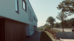 Ein modernes Gebäude mit flacher Fassade, großen Fenstern und einem gepflasterten Weg.