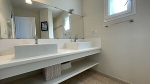 Uma casa de banho com duas pias, um espelho grande e uma janela.