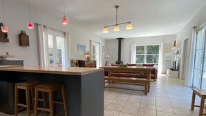 Cozinha espaçosa com uma ilha grande, banquetas de madeira e um espaço de refeições com bancos.