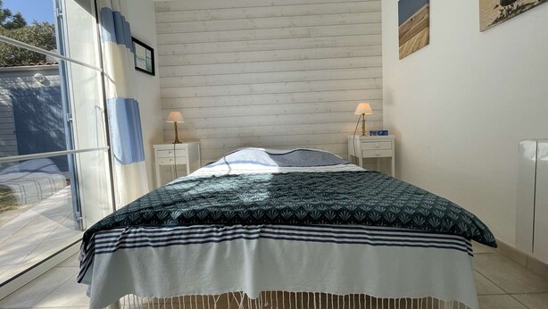 Quarto com cama, duas mesas de cabeceira, uma janela e uma obra de arte pendurada na parede.