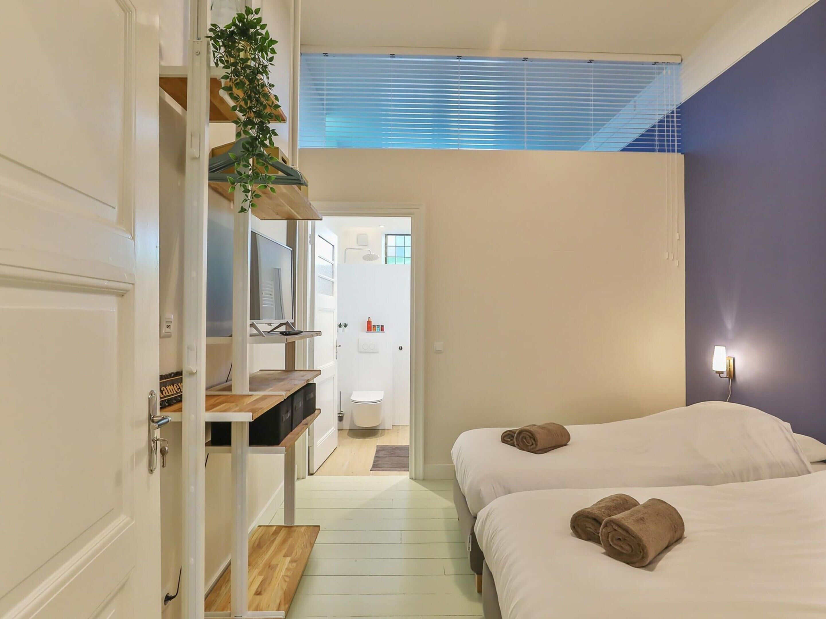 Une chambre d’hôtel avec deux lits, une télévision, une douche et un petit coin cuisine.