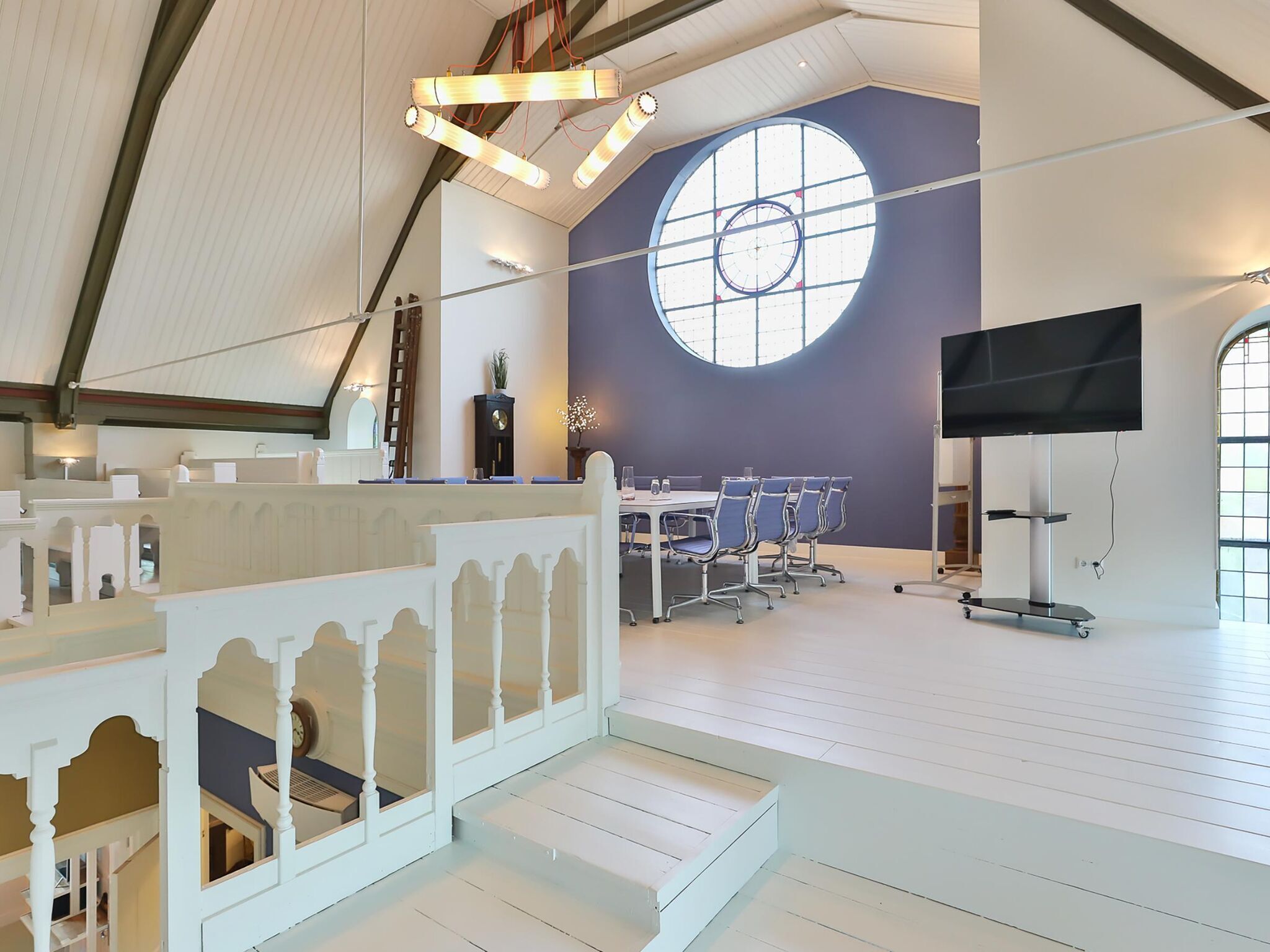 A spacious room with a large window, a flat-screen TV, and a conference table with chairs.