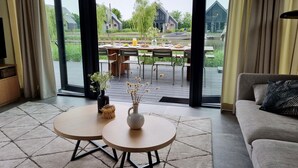 Ein modernes Wohnzimmer mit einem großen Schiebeglasfenster, das in einen Essbereich im Freien führt.