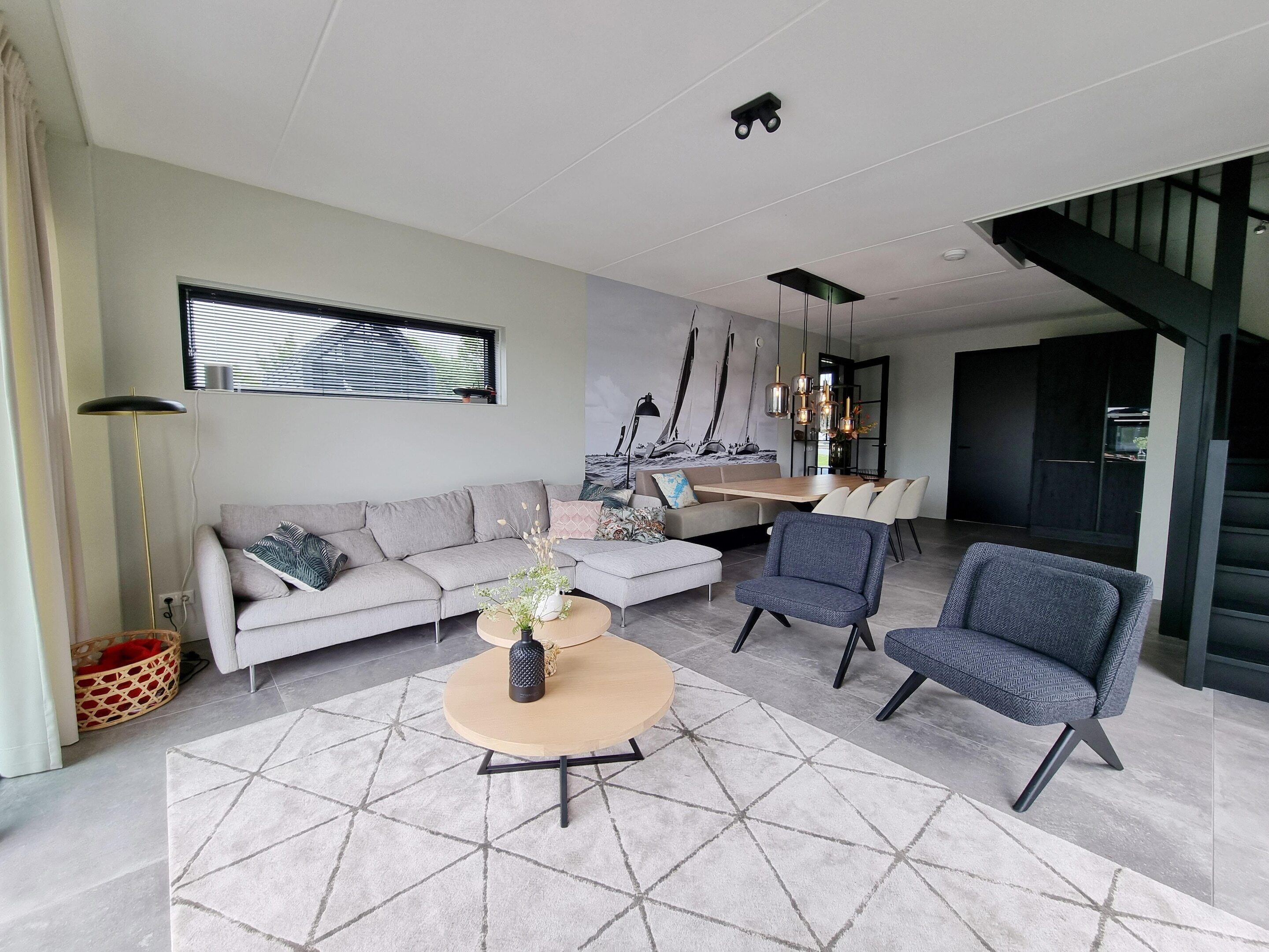 A modern living room with a sofa, chairs, a coffee table, and a dining area with a table and chairs.