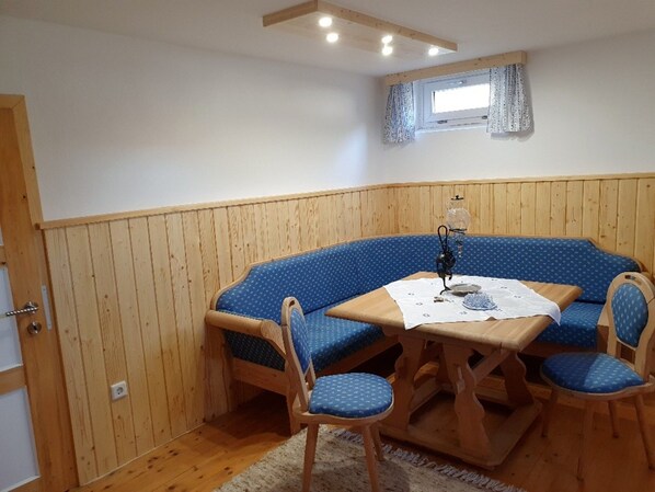 A corner room with a wooden bench and table, a window with curtains, and a door. - Holiday Home in Altmelon Near Weinsberg Forest (Altmelon)
