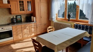 Una cocina con armarios de madera, estufa y una mesa de comedor con sillas.