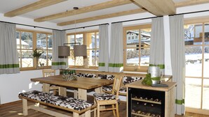 Puisesta materiaalista valmistettu ruokailutila, jossa on penkki, viiniteline ja suuret ikkunat, joissa on verhot.