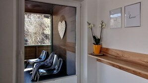 A modern interior with a glass door leading to an outdoor seating area, a heart-shaped decoration, and framed artwork on the wall. - Hochkonig Holiday With Panoramic Views (Dienten am Hochkoenig)