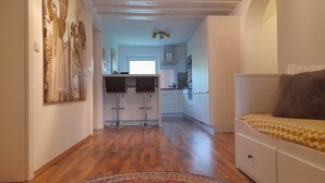 A modern kitchen with two bar stools, a dining area with a patterned rug, and a bedroom with a bed and a nightstand. - Hochkonig Holiday With Panoramic Views (Dienten am Hochkoenig)