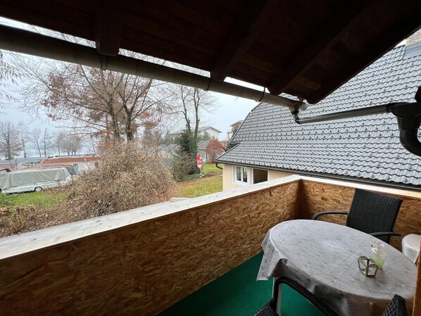 Een kamer met uitzicht op een huis, een tafel en een stoel.
