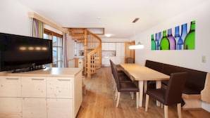 A modern kitchen with wooden cabinets, a built-in stove, and a dining area with a wooden table and benches.