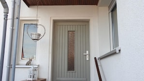 Une porte d’entrée ornée d’un panneau décoratif, une petite fenêtre au-dessus, et un plafond en bois.