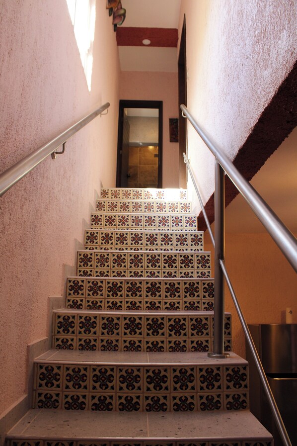 Una escalera con baldosas estampadas, barandillas de metal y una puerta en la parte superior.