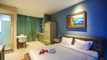 A hotel room with a bed, a painting, a desk, and a chair.