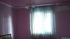Een slaapkamer met een bed, een stoel en een raam met gordijnen.