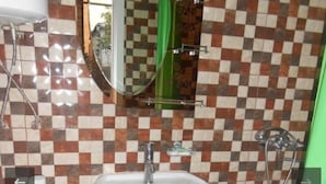 Een badkamer met een wit wastafeltje op voet, een toilet en een douchehoek.