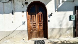 A wooden double door with a decorative panel design, a small step leading up to it, and a metal vent on the ground. - Wonder House & Panoramic View on the Amalfi Coast (Amalfi)