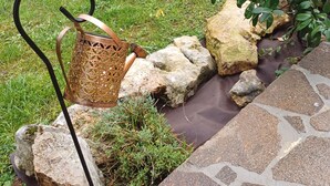 Een tuin met een metalen stoel, een pad van stenen en een klein waterpartij.