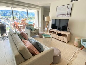 A living room with a sofa, TV, and a view of a marina.