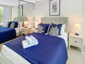 A hotel room with a large bed, two bedside tables, a mirror, and a framed picture on the wall.