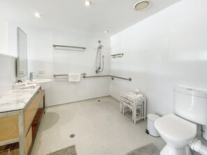 A modern bathroom with a sink, mirror, toilet, and shower.