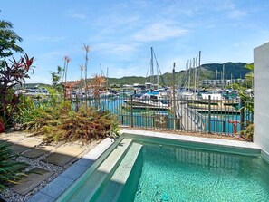 A marina with boats, a swimming pool, and a mountainous backdrop.