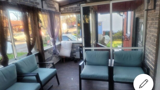 A cozy outdoor seating area with cushioned chairs and a table, large windows with curtains, and a view of the street. - 2 bed Room Quite and Central House in Orebro (Örebro)