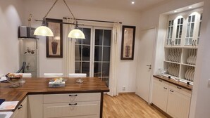 A modern kitchen with wooden cabinets, a central island, pendant lighting, and a view of the dining area. - 2 bed Room Quite and Central House in Orebro (Örebro)