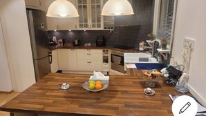 A kitchen with wooden countertops, a central island with a fruit bowl, and two pendant lights. - 2 bed Room Quite and Central House in Orebro (Örebro)