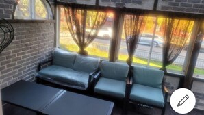 A seating area with a brick wall, a window with curtains, and a view of the street. - 2 bed Room Quite and Central House in Orebro (Örebro)