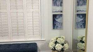 A room with a dark blue bench, a large mirror, and a wall with four framed pictures of waterfalls.