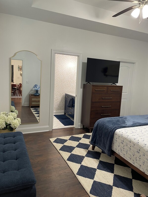 Un dormitorio con cama, cómoda, televisor y espejo.