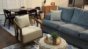 A living room with a grey sofa, wooden chairs, a coffee table, and a patterned rug.