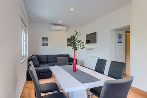 Un salon moderne avec un canapé, une table à manger et des chaises, un vase rouge et une plante en pot.
