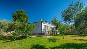 A small house with a tiled roof, a chimney, and a covered patio area. - Chill out . (Marcana)