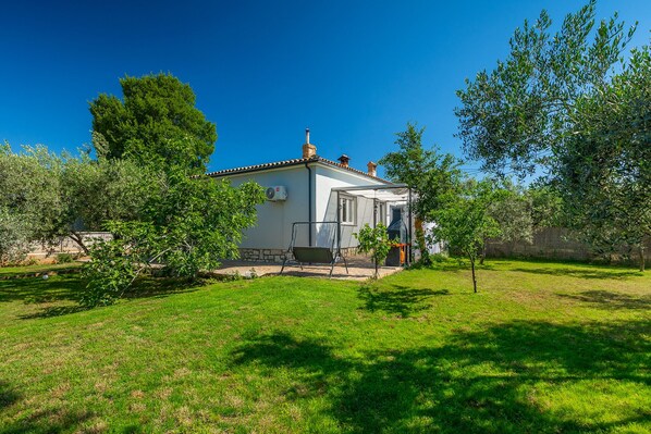 Une petite maison avec un toit en tuiles, une cheminée et un patio abrité.