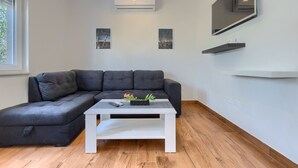 A modern living room with a sectional sofa, a white coffee table, and two wall-mounted air conditioners. - Chill out . (Marcana)